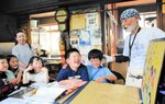 井上社長（右端）自作の紙芝居に聞き入る児童たち＝３日、香美町村岡区福岡の香味煙