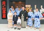 　部屋の前で力士や家族らと記念写真に納まる秀ノ山親方（中央）＝２０日、東京都墨田区