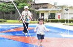 厳しい暑さに噴水で涼を求める親子連れ＝３日、鳥取市戎町の真教寺公園