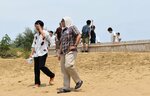 暑さの中タオルを被って砂丘を歩く観光客ら＝３日、鳥取市の鳥取砂丘