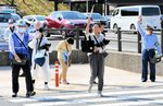 手を挙げてモデル横断歩道を渡る歩行者＝１７日、鳥取市の鳥取砂丘入り口付近