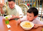 八頭町産エリンギの天ぷらが載ったうどんを味わう子どもと保護者