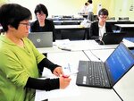２人の要約筆記者がパソコンで打ち込む文字を読み取る聴覚障害者（手前）