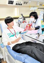 説明を受けながら献血に臨む生徒＝１３日、新温泉町芦屋の浜坂高