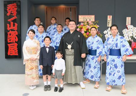 　部屋の前で力士や家族らと記念写真に納まる秀ノ山親方（中央）＝２０日、東京都墨田区
