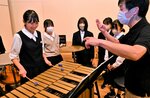鳥取ウインドシンフォニカの団員（右）の手ほどきを受ける生徒ら