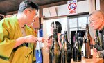 この道２０年以上のベテラン但馬杜氏の説明で３種類の日本酒を試飲する来館者（左）＝５月３１日、新温泉町湯の杜氏館