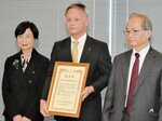 表彰状を掲げる井田氏（中央）＝１８日、東京都千代田区