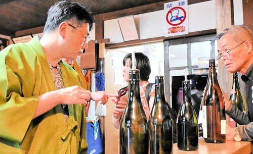 この道２０年以上のベテラン但馬杜氏の説明で３種類の日本酒を試飲する来館者（左）＝５月３１日、新温泉町湯の杜氏館