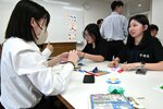 鳥取敬愛高の生徒（左）と一緒に折り紙を楽しみ会話を弾ませる亨碩高の生徒＝２２日、鳥取市西町１丁目の鳥取敬愛高