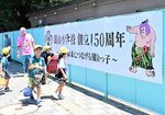 通学路のフェンスに設置された記念の横断幕を眺める児童
