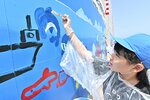巨大なケーソンに自由に絵を描く児童＝１９日、鳥取市港町の鳥取港１号岸壁