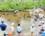 竹ざおを使ってニジマス釣りに挑戦する児童ら＝香美町村岡区村岡の昆陽川（村岡区中央公民館提供）