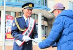 チラシを渡して交通安全を呼びかける一日米子署長の瀬川さん（左）＝９日、米子市末広町