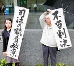 　生活保護費の基準額引き下げを巡る訴訟の控訴審判決を受け、福岡高裁前で「不当判決」などと書かれた紙を掲げる原告ら＝２１日午後