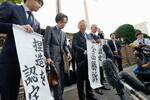 　大川原化工機訴訟の東京高裁判決を受け、「全面勝訴」と書かれた紙を手にする大川原正明社長ら＝２８日午後、東京高裁前