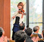 窓越しの紅葉を背にバイオリンを奏でるＡｙａｓａさん＝２９日、江府町御机の鏡ケ成キャンプ場