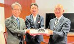 浦川社長（左）からプロジェクターを受け取る吉川校長（右）