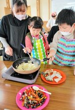 スズキとシジミのパエリアを作る親子＝１９日、米子市彦名新田の米子水鳥公園ネイチャーセンター