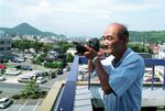 ２００５年の定点写真を撮影する石賀敬之氏＝９月１日、倉吉市の県中部総合事務所