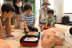 ＡＥＤの使い方を学んでボタンを押す子ども子どもたち