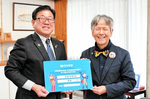 広田市長に巨大パスポートを手渡し、子どもたちの来館を呼びかける稲嶋社長（右）