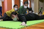 うつぶせになった入江さんを力を合わせてひっくり返す子どもたち＝２１日、鳥取市のヤマタスポーツパーク県民体育館