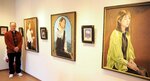 野津さんと、身近な女性や風景などを描いた油絵が並ぶ会場