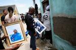 　亡くなったトニ・ブランコさんの写真を持つ人々＝１０日、ドミニカ共和国・サントドミンゴ近郊（ロイター＝共同）
