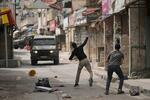 　９日、イスラエルが占領するヨルダン川西岸で、イスラエル軍の車両に石を投げるパレスチナ人（ＡＰ＝共同）