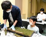 土を敷いた育苗箱の上に芝生を敷く参加者ら＝１０日、倉吉未来中心セミナールーム
