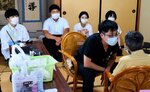 巡回診療の様子を見学する医学生（後列）＝２１日、日南町上萩山の上萩山つるぎ会館