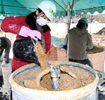 ミキサーでもみ殻と消石灰水を混ぜる参加者＝１２日、鳥取市鹿野町鹿野の鳥の劇場
