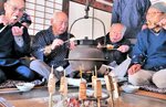 いろりで焼いた豆腐を食べる会員ら＝８日、鳥取市河原町渡一木の河原歴史民俗資料館