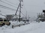 幹線道路沿いの歩道の雪かきをする住民＝25日午前10時ごろ、米子市石井