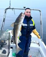 　釣り上げた魚を手に持つ漁師のヌカさん＝２０２４年６月、グリーンランド・ヌーク沖（本人提供）