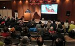 ゴロ画伯さん（奥）が演じるエレキ紙芝居を楽しむ観客