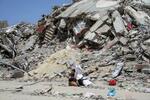 　イスラエル軍の空爆で破壊された建物のがれき近くに座る少年＝４月２２日、ガザ地区北部（ロイター＝共同）