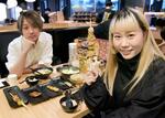 　鳥貴族の中国大陸１号店で焼き鳥を楽しむ女性会社員（右）ら＝２０２５年３月、中国上海市（共同）