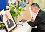 青木氏の遺影が飾られた記帳台で名前を記す関係者＝１２日、松江市内中原町