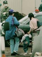 　２歳ぐらいの子供の手を引き「第６サティアン」から出てきた女性信者＝１９９５年３月、山梨県上九一色村
