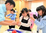 高校生（左）の手を借りながらバルーンアートを楽しむ子どもたち