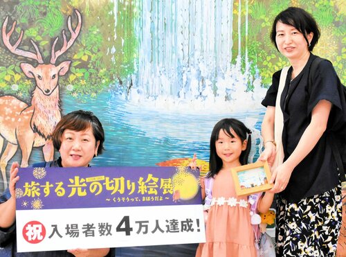 酒井さん（左）から受け取った記念品を手にする寺本さん＝２６日、境港市の夢みなとタワー
