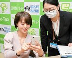スマートフォンでの確定申告を体験する森谷さん（左）＝１５日、米子市東町の米子税務署