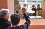 ホームで見送る祖父母（手前）に手を振る西川さん家族＝６日、ＪＲ米子駅