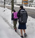 雪道を通学する小中学生＝25日午前９時１０分ごろ、米子市両三柳