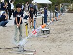 空気を送り込んだペットボトルロケットを打ち上げる子どもら＝４日、鳥取市浜坂
