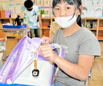 配布されたクマよけ鈴をランドセルに着けた児童＝１９日、新温泉町諸寄の浜坂西小