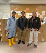 寿製菓の菓子１５００箱を志賀町に届けた寺谷さん（右）と森下支店長（中央）