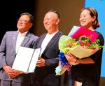 広田市長（左）から委嘱状を手渡され、笑顔で撮影に応じる足立さん（中央）＝１２日、倉吉市のエースパック未来中心